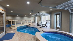An indoor swimming pool with a hot tub, sun loungers, and a covered area with a roof. - Renewed Spirit 7 Bedroom Cabin with Heated Pool (Sevierville)