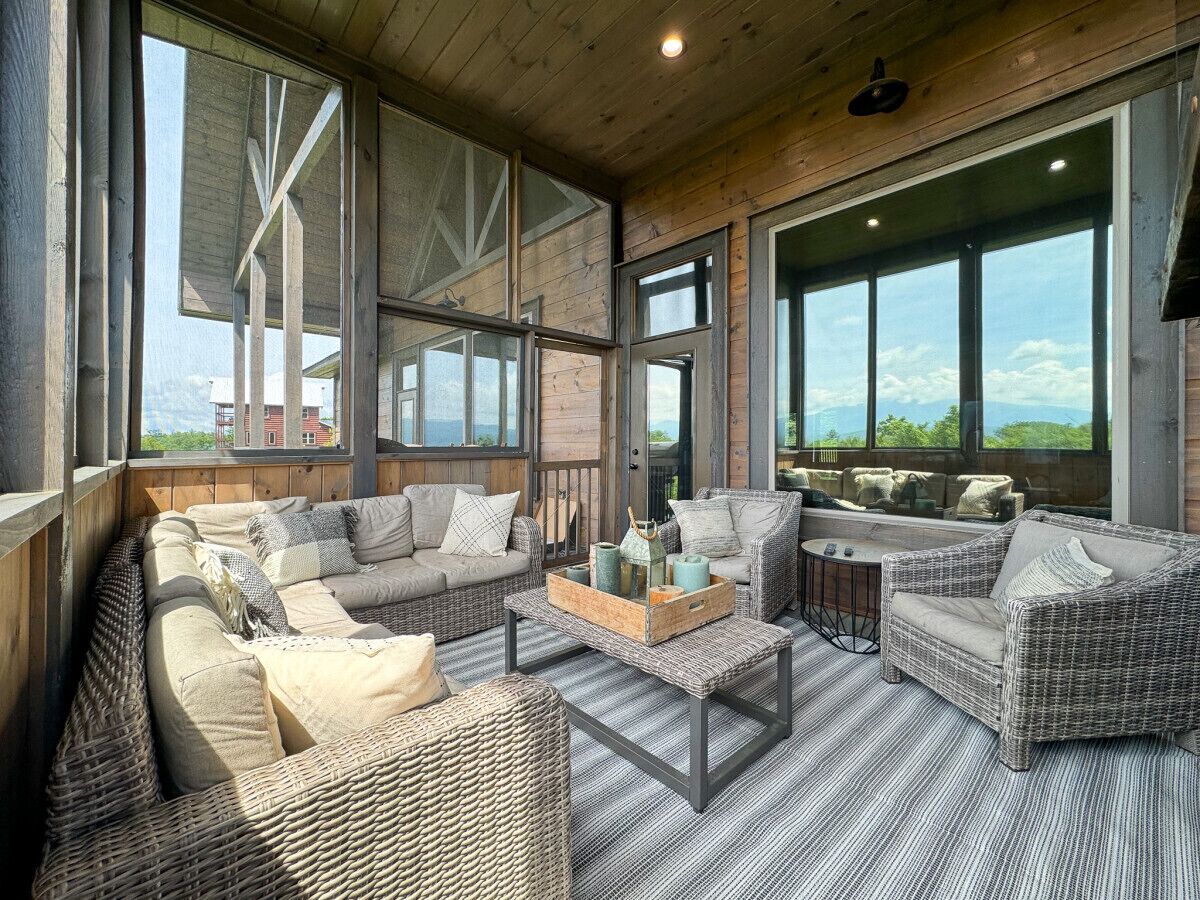 A spacious living area with wicker furniture, large windows, and a view of the outdoors.