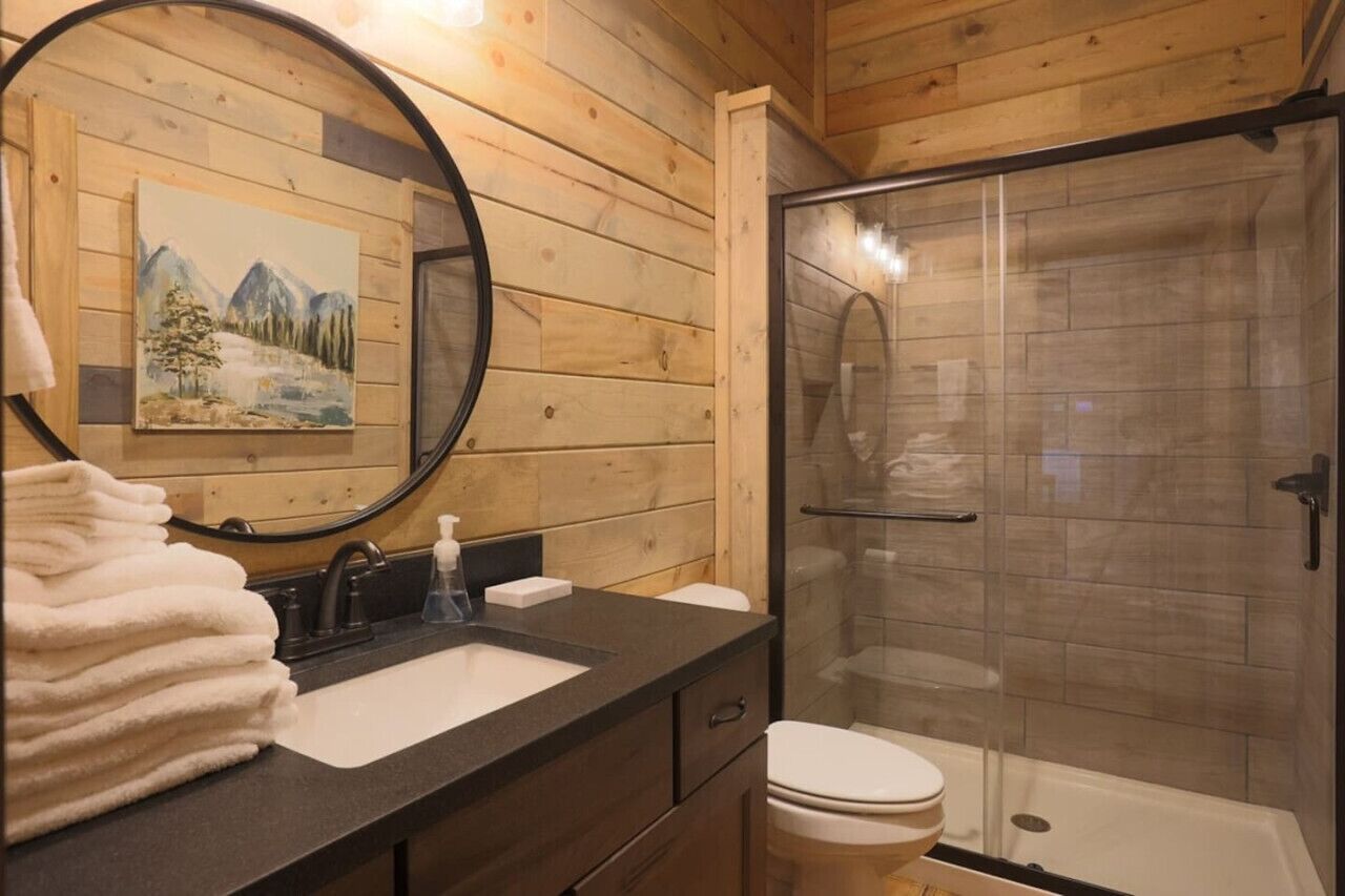 A wooden cabin bathroom with a sink, mirror, and toilet.