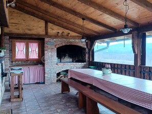 A rustic kitchen with a brick oven, wooden beams, and a large table with a checkered tablecloth. - Stara Hiža Vlašić (Žumberak)