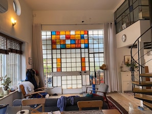 Uma sala de estar com uma janela grande, uma escada e um sofá.