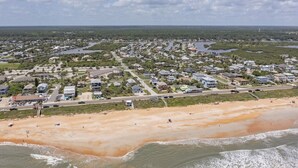 Vista aérea de una zona residencial costera con casas, caminos y una playa.