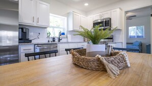 Una cocina moderna con armarios blancos, electrodomésticos de acero inoxidable y una mesa de comedor de madera.
