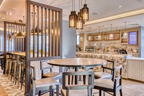 A modern bar area with a bar counter, stools, and hanging pendant lights. - Premier Inn London Canary Wharf - Westferry (London)