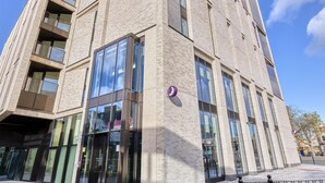 A multi-story building with a brick facade, large windows, and balconies. - Premier Inn London Canary Wharf - Westferry (London)
