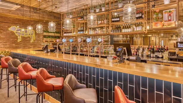 A bar area with a wooden ceiling, hanging lights, a neon animal sign, and a variety of bottles and glasses on shelves. - Premier Inn Birmingham Cc Exchange Square (Birmingham)