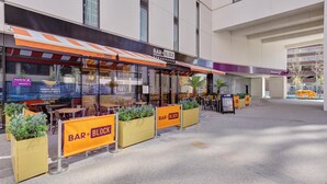 A Bar+Block Steakhouse with outdoor seating, a Premier Inn sign, and a visible parking area. - Premier Inn Birmingham Cc Exchange Square (Birmingham)