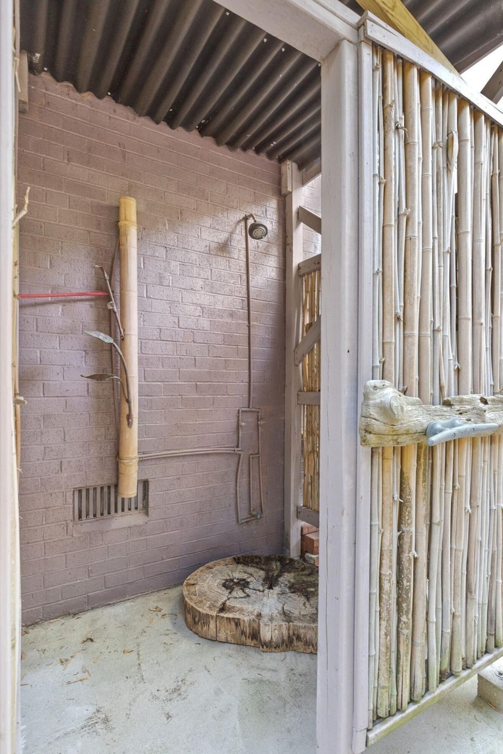 Una habitación con pared de ladrillo, estructura de bambú y un tronco de madera.
