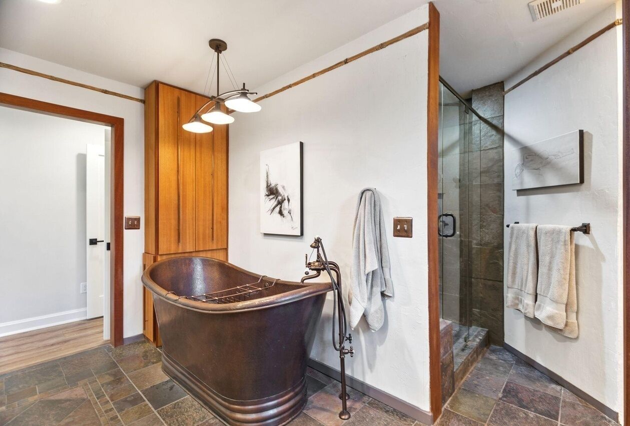 A modern bathroom with a freestanding bathtub, a glass shower enclosure, and a wooden accent wall.
