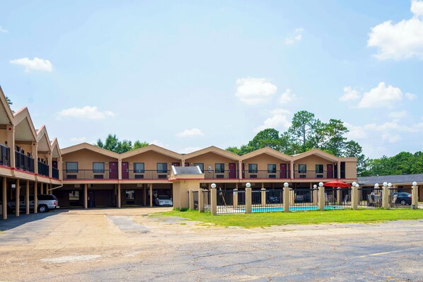 A motel with multiple two-story buildings, a swimming pool, and a parking lot. - OYO Hotel Opp AL Floral Hwy (Opp)
