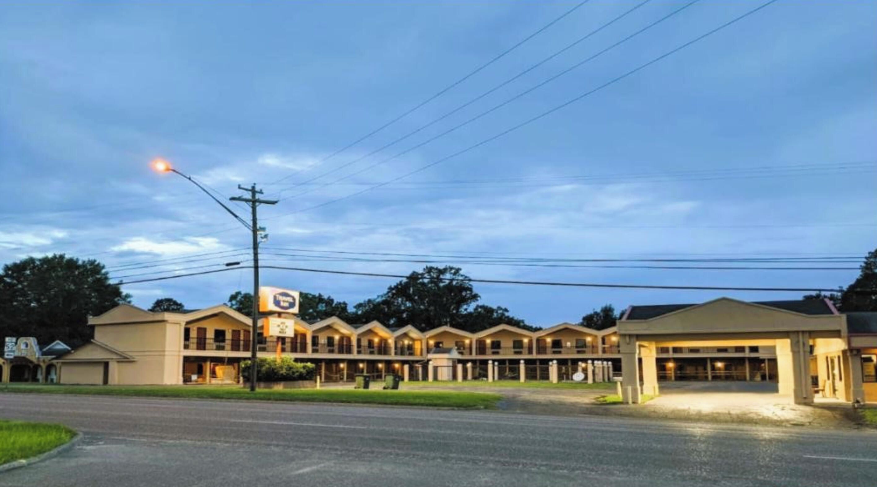 A motel with multiple units, a parking lot, and a clear sky.