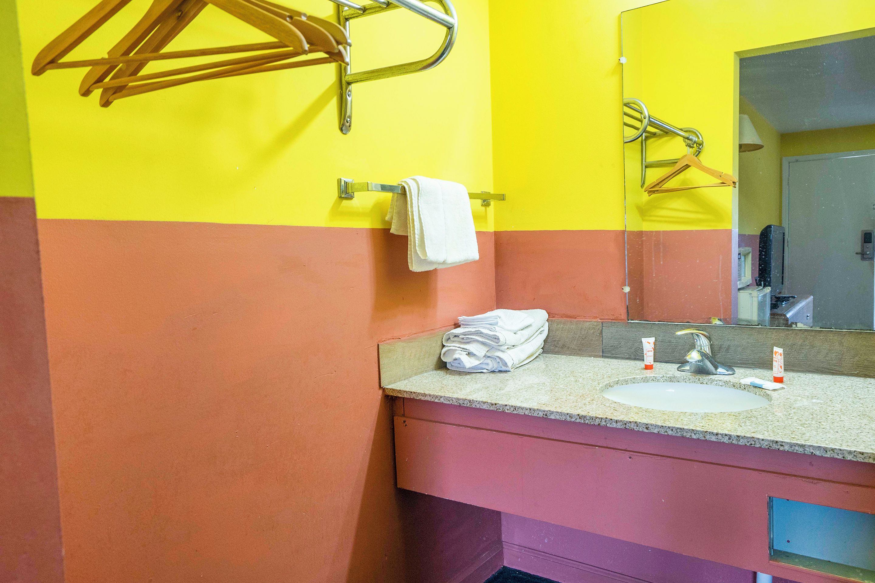 Een badkamer met een wastafel, spiegel, handdoekrek en toilet.