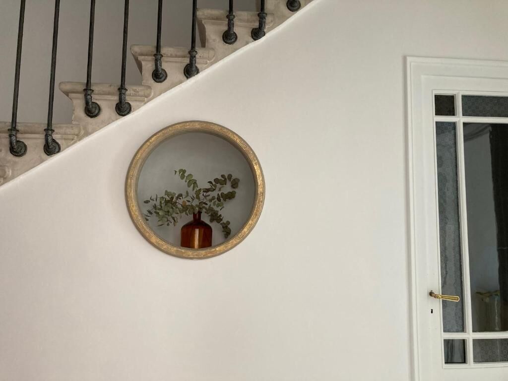 Una escala al costat d'una paret blanca i una porta amb un panell de vidre.
