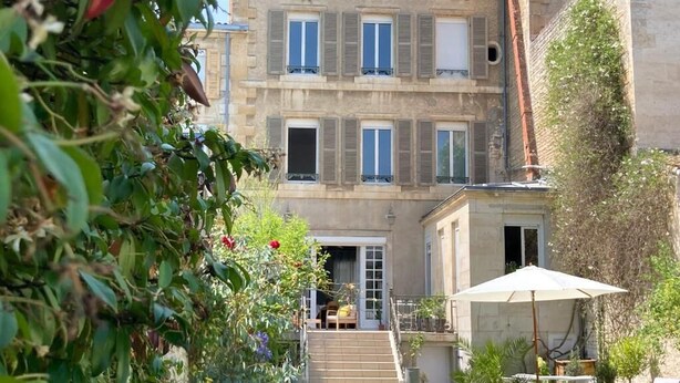 A multi-story building with a garden area in front, featuring a staircase leading to the entrance. - La Maison 19 (Niort)