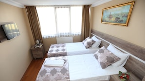 A hotel room with two beds, a television, a painting, and a window with curtains. - My Holiday Time Hotel (Istanbul)