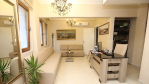 A living room with a sofa, a coffee table, a TV stand, and a potted plant. - My Holiday Time Hotel (Istanbul)