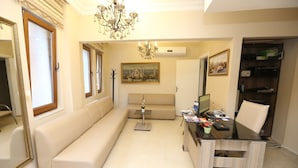 A living room with a beige sofa, a glass coffee table, a desk with a computer, and a bookshelf. - My Holiday Time Hotel (Istanbul)