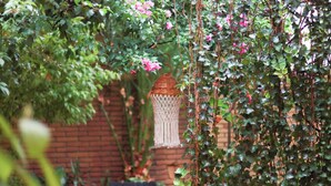 Un jardin agrémenté d’une lanterne en osier, d’un banc et d’un mur en briques.