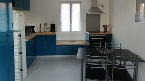 Una cucina compatta con mobili azzurri, forno integrato, macchina da caffè e una finestra che lascia entrare luce naturale.