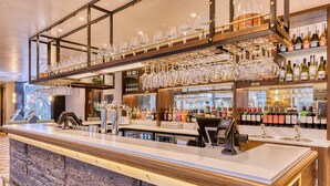 Un espace bar doté d’un long comptoir, de verres à vin disposés sur des étagères et d’une variété de bouteilles.