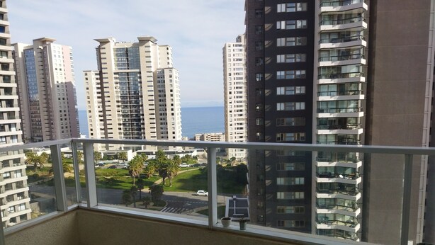 Ein Balkon mit Blick auf hohe Gebäude und eine Straße mit Palmen.
