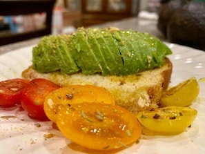 A plate with avocado slices, cherry tomatoes, and pickled vegetables. - The Sanctuary On Huron River (Flat Rock)