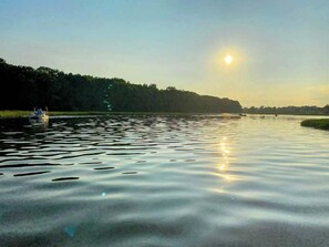 A calm river with a boat on the left and a forested bank. - The Sanctuary On Huron River (Flat Rock)