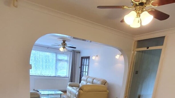 Uma sala espaçosa com uma mesa de jantar de madeira, um sofá de couro e um ventilador de teto.