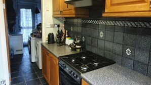 Cozinha com armários de madeira, fogão e painel de azulejos.