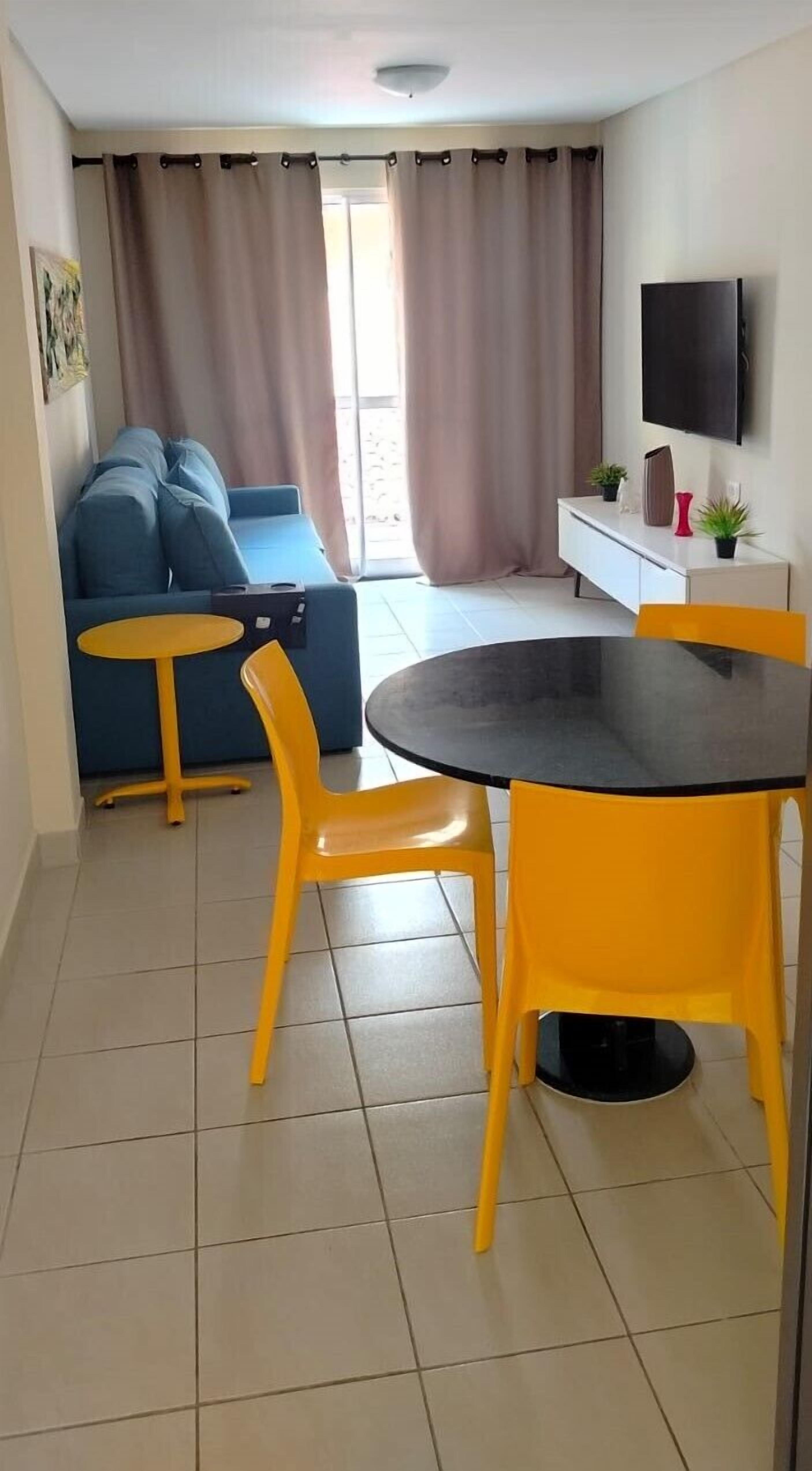 Um espaço compacto com sofá, mesa redonda pequena e duas cadeiras.