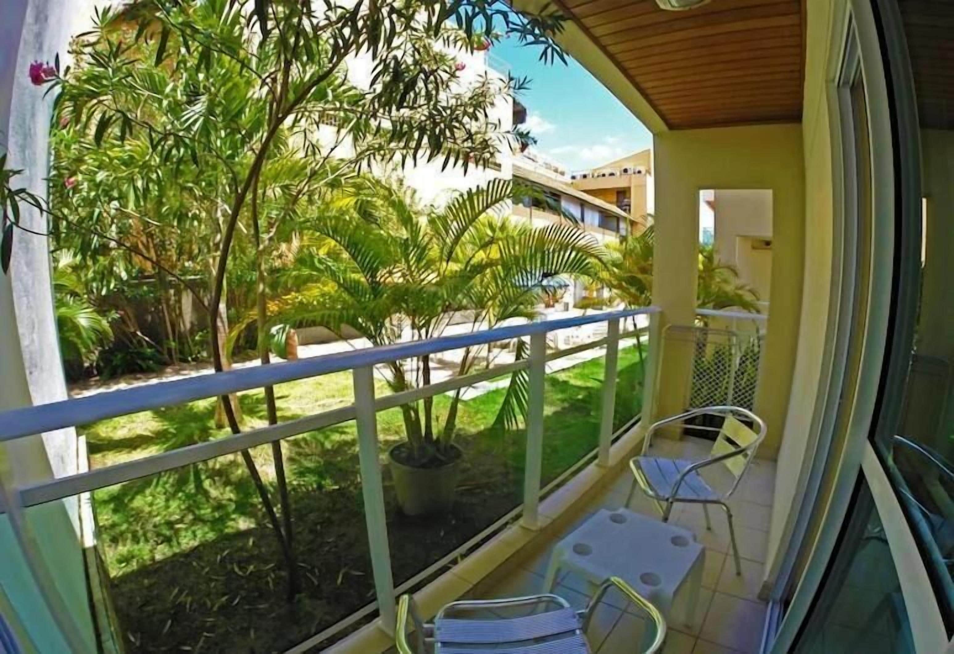 Un balcone con vista su un giardino, un tavolo con sedie e una pianta in vaso.