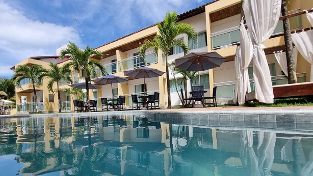 A poolside area with a clear pool, umbrellas, and lounge chairs. - Pousada Agua Viva (Ipojuca)