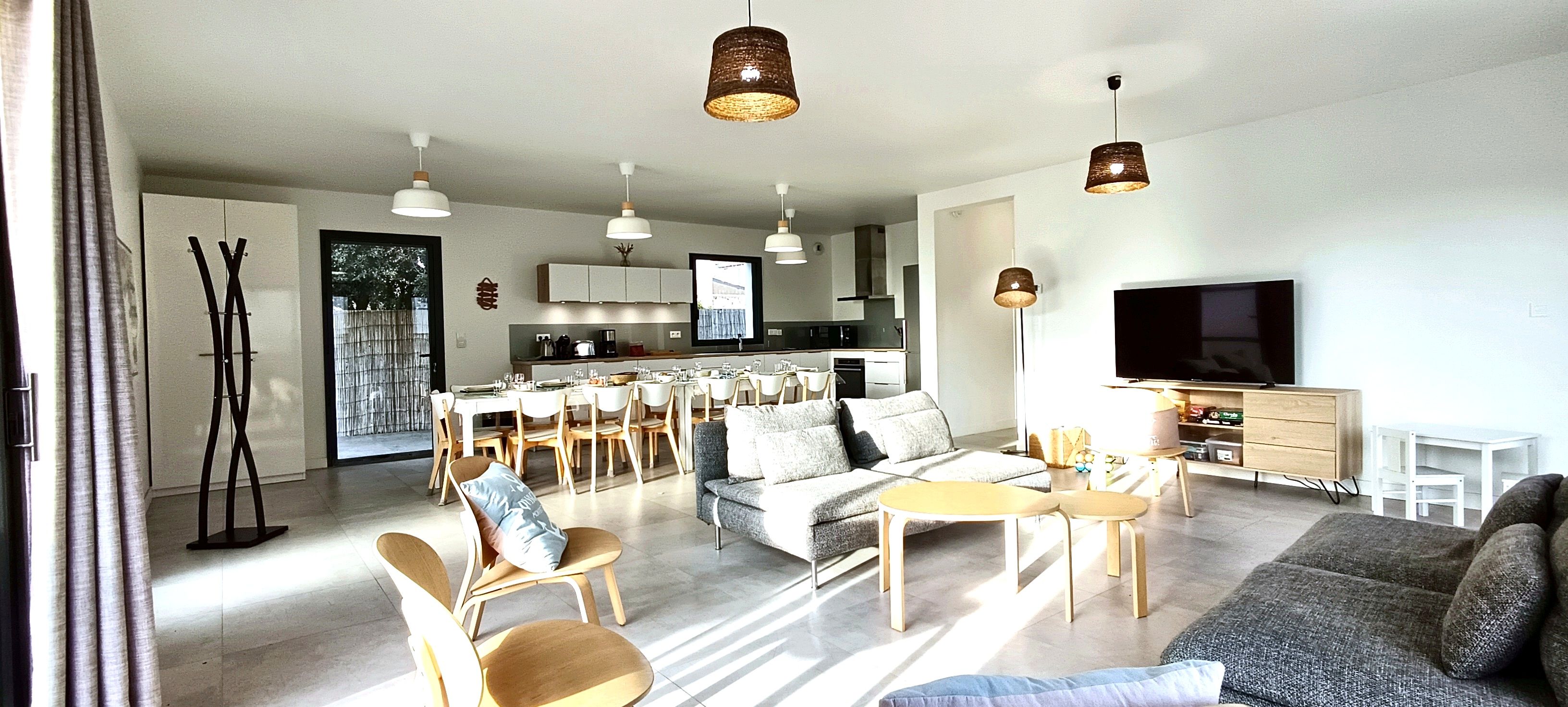 A modern living room with a sofa, chairs, a dining area, and a kitchen in the background.