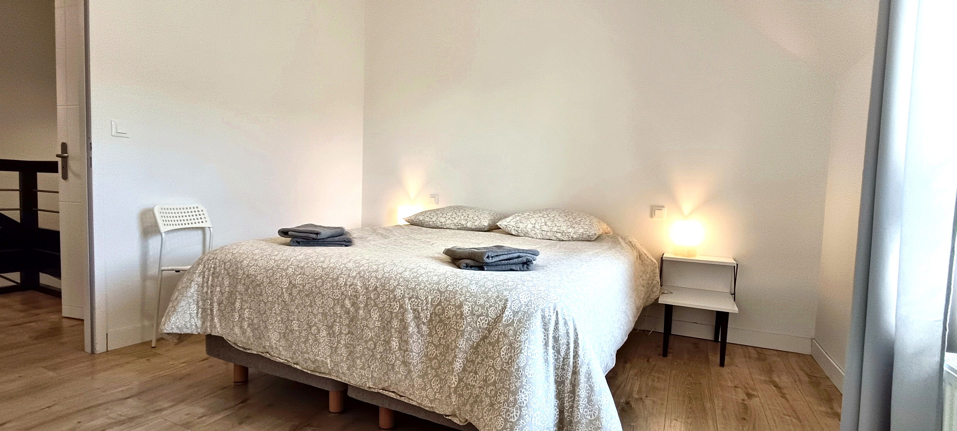 Une chambre à coucher avec un lit, deux tables de chevet, une chaise et une porte.