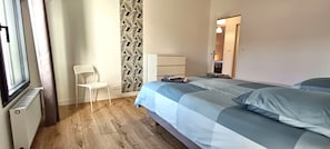 A bedroom with a bed, a chair, a radiator, and a wall with a leaf pattern.