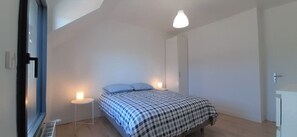 A bedroom with a bed, bedside lamps, a wardrobe, and a window.