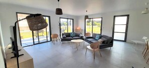 Un salon spacieux comprenant un canapé, des fauteuils, une table basse et un téléviseur.