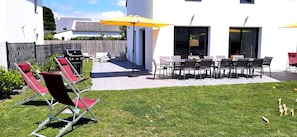 A patio area with outdoor furniture, a grill, and a yellow umbrella.