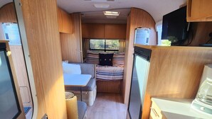 Interni di un camper compatto, con angolo cottura, zona pranzo e cuccetta.
