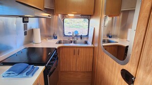 Una cucina compatta con mobili in legno, un fornello, un lavello e una finestra con persiane.