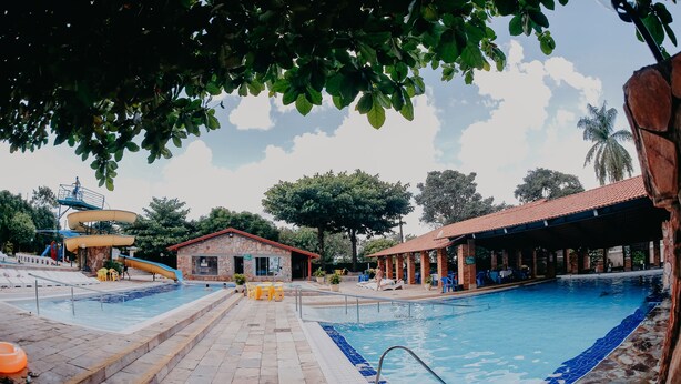 A swimming pool area with a water slide, a small building, and a covered seating area. - Imperio Romano Thermas Hotel -BVTUR (Caldas Novas)