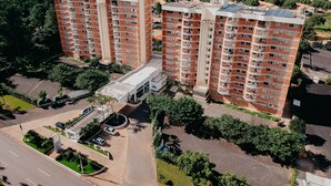A high-rise residential building with multiple balconies, a parking area, and a landscaped courtyard. - Imperio Romano Thermas Hotel -BVTUR (Caldas Novas)