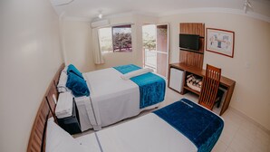 A hotel room with two beds, a desk, a TV, and a balcony with a view. - Imperio Romano Thermas Hotel -BVTUR (Caldas Novas)