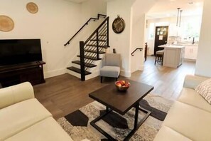 Relax in this stylish living room with a flat-screen TV, comfortable sofa, and a staircase leading to an upper level.