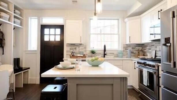 A modern kitchen with white cabinetry, a central island, a built-in oven, and a stainless steel refrigerator. - Comfy Cherry Blossom Townhouse / Easy DC Access (Washington)