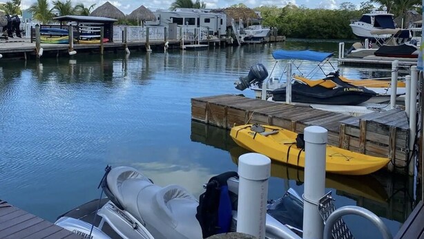 A marina with boats docked, a jet ski, and a kayak on a wooden dock. - Delightful RV in Key Largo, FL (Key Largo)