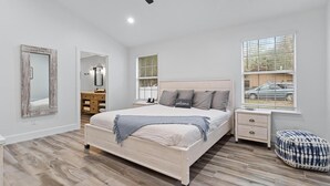 Ein Schlafzimmer mit Bett, Nachttischen, Deckenventilator und Fenstern.