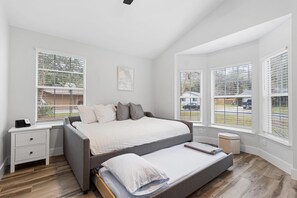 Un dormitorio con una cama grande, una mesita de noche y una ventana con persianas.