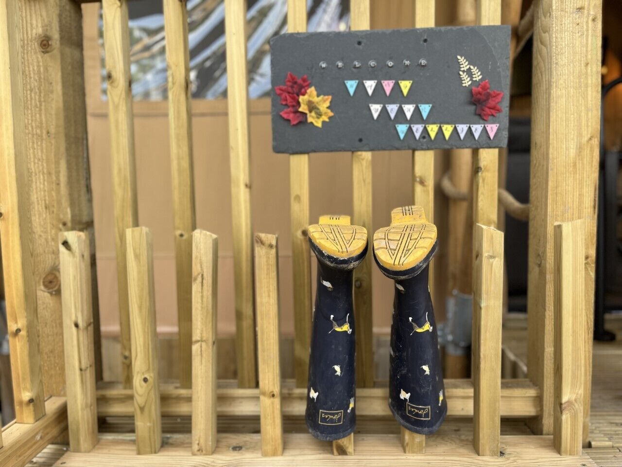 A pair of shoes with a black and yellow design, mounted on a wooden structure with a black sign featuring colorful triangular flags and flowers.