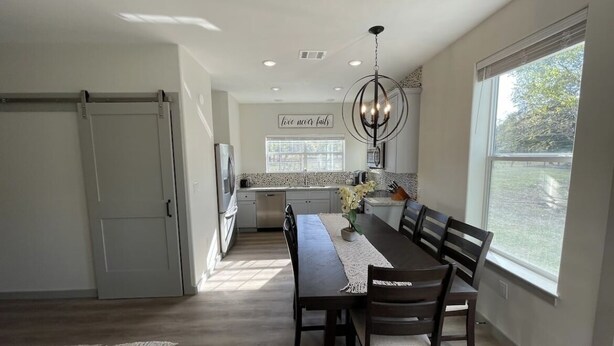 A modern kitchen with a dining area, large windows, and a chandelier. - Country Oasis -B (Hockley)